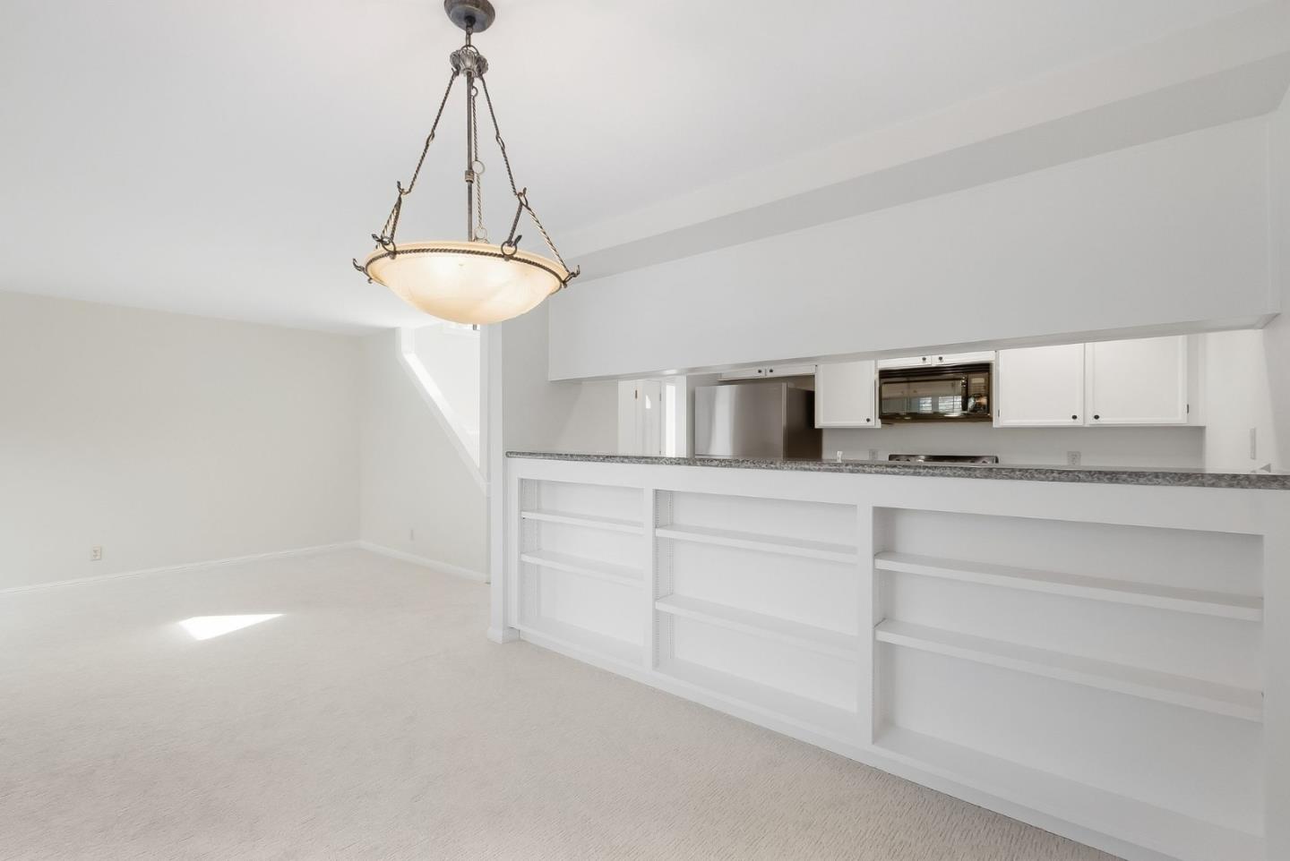 Empty dining area with a pendant light and built-in shelving at the kitchen pass-through.