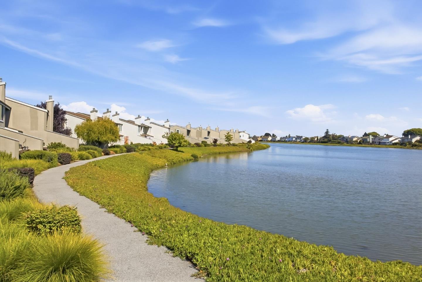 Residential homes line a lagoon beside a landscaped walking path.