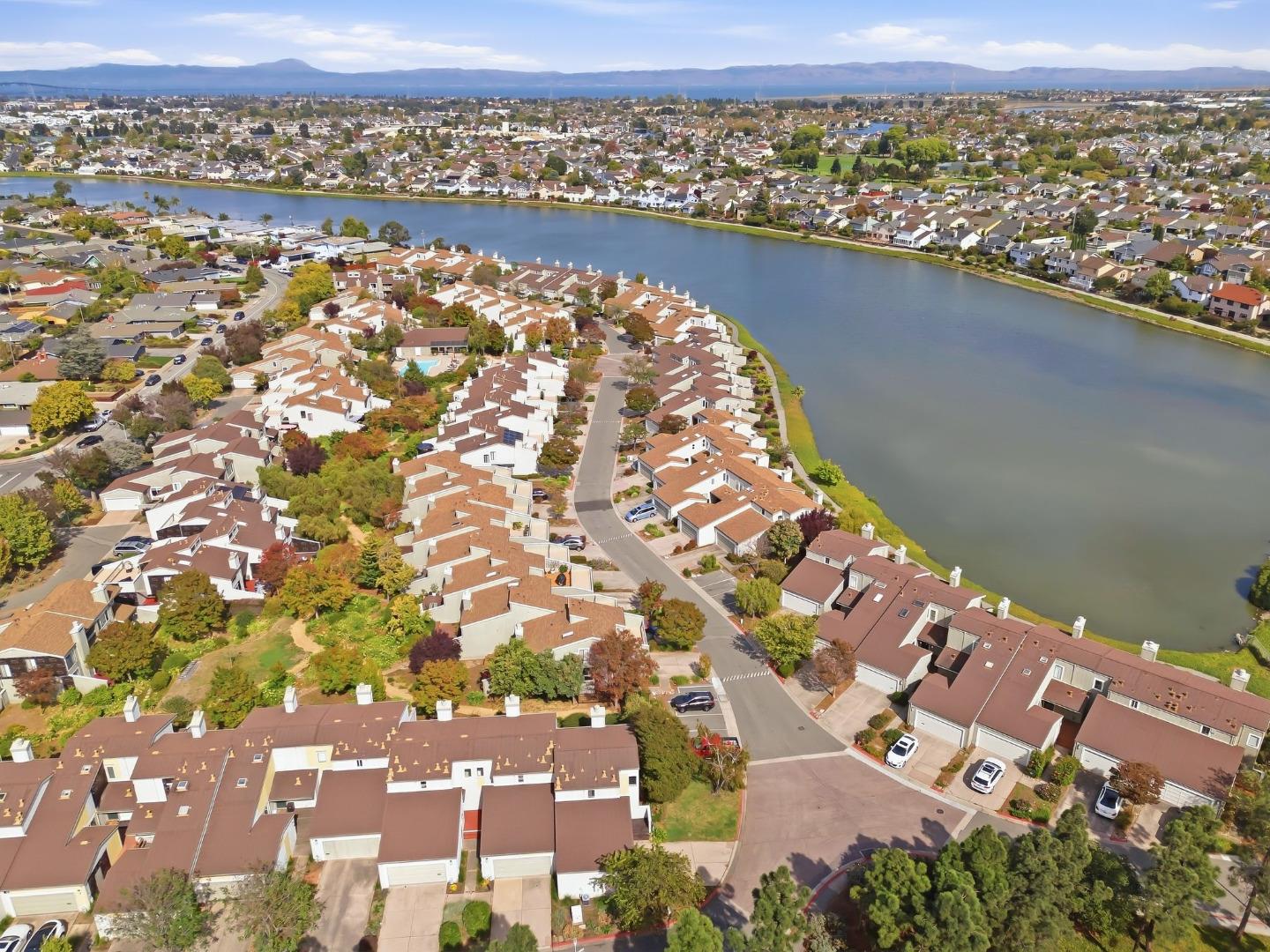 Aerial view of homes along a lake, with distant hills beyond the neighborhood.