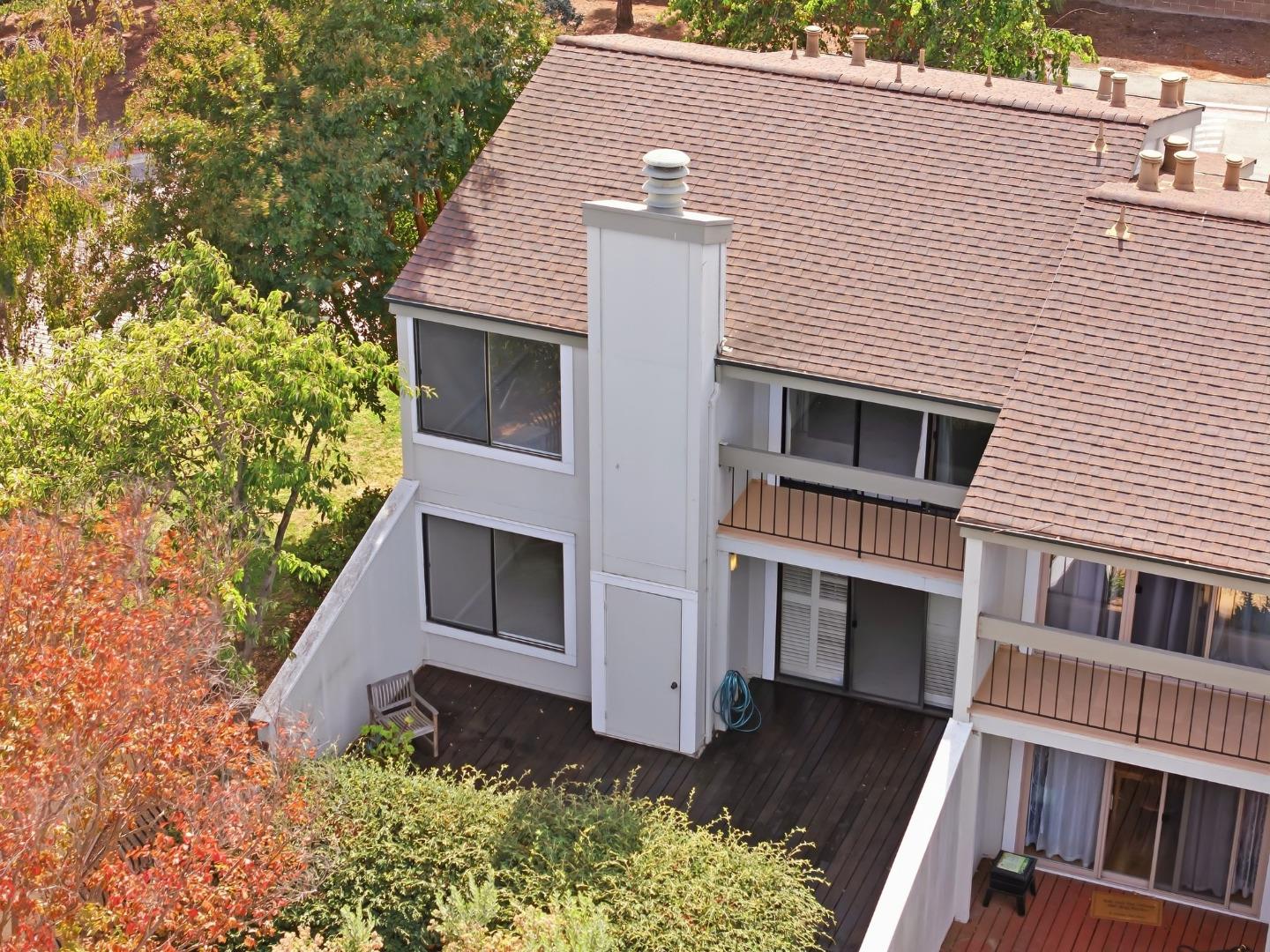 Elevated view of a home with a broad shingle roof, balconies, and a wood deck among trees.