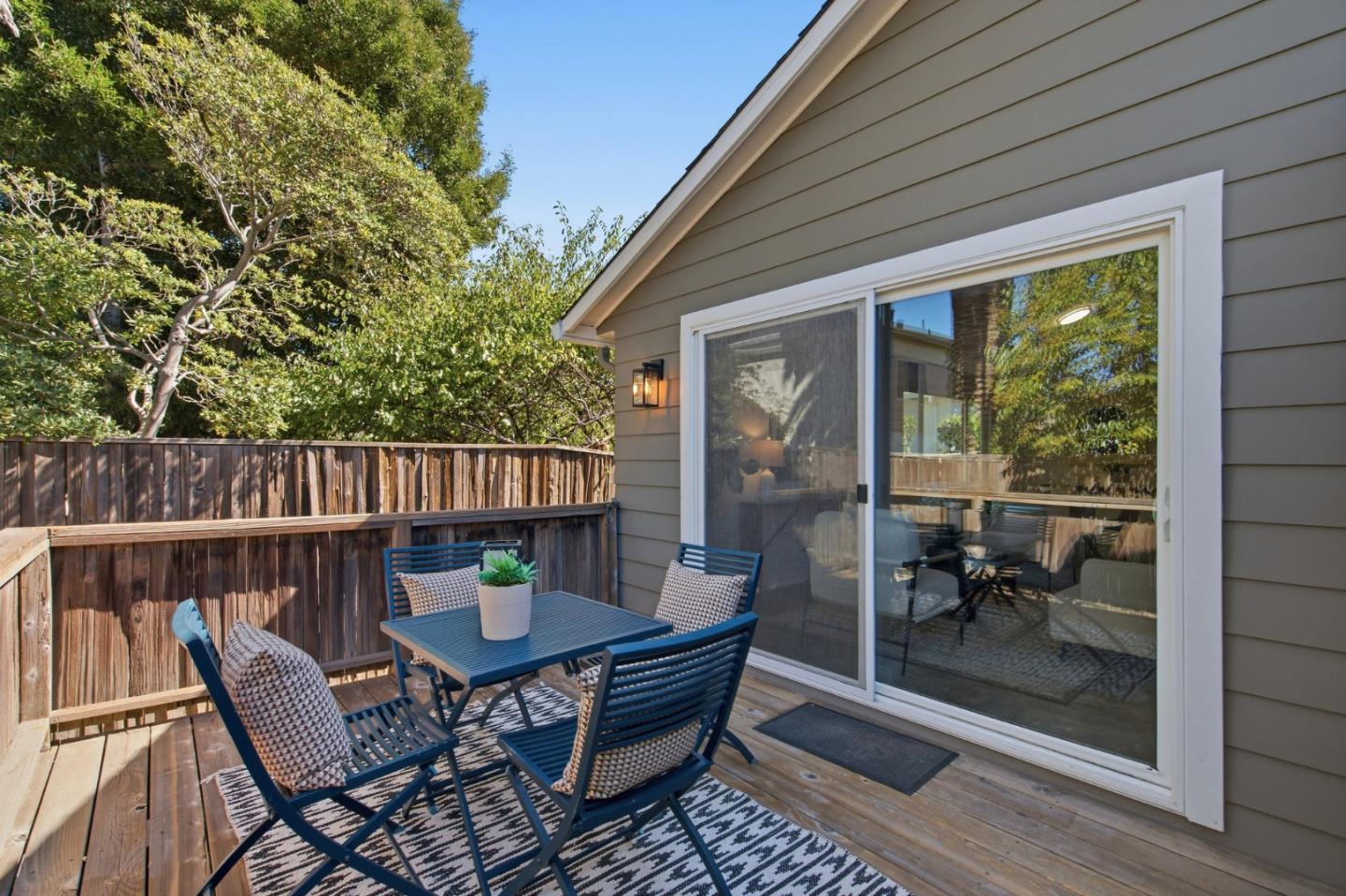 Wooden deck with blue patio furniture beside a gray home and sliding glass door.