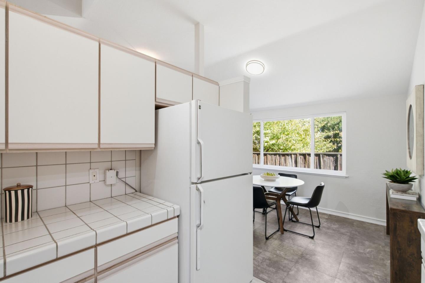 Kitchen with tiled counters and a dining nook beside a large window.