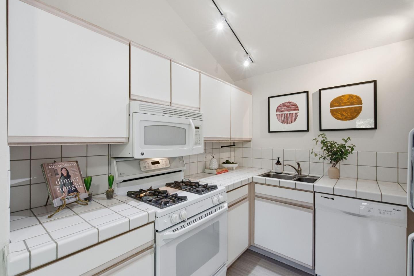 White kitchen with tiled counters, a gas range, microwave, double-basin sink, and dishwasher.