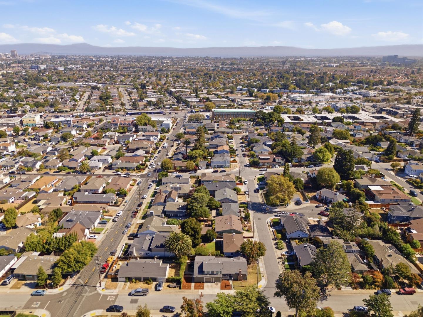 Aerial view of San Mateo homes and streets, with a distant mountain ridge.