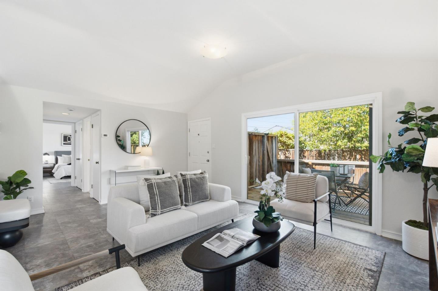 Staged living room with sliding doors opening onto a furnished patio and fenced yard.