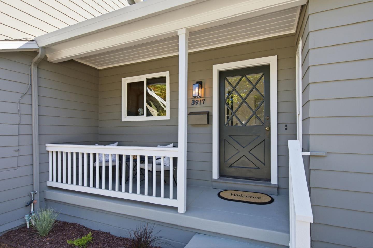 Home’s covered front porch with white railings and a dark glass-paneled door marked 3917.