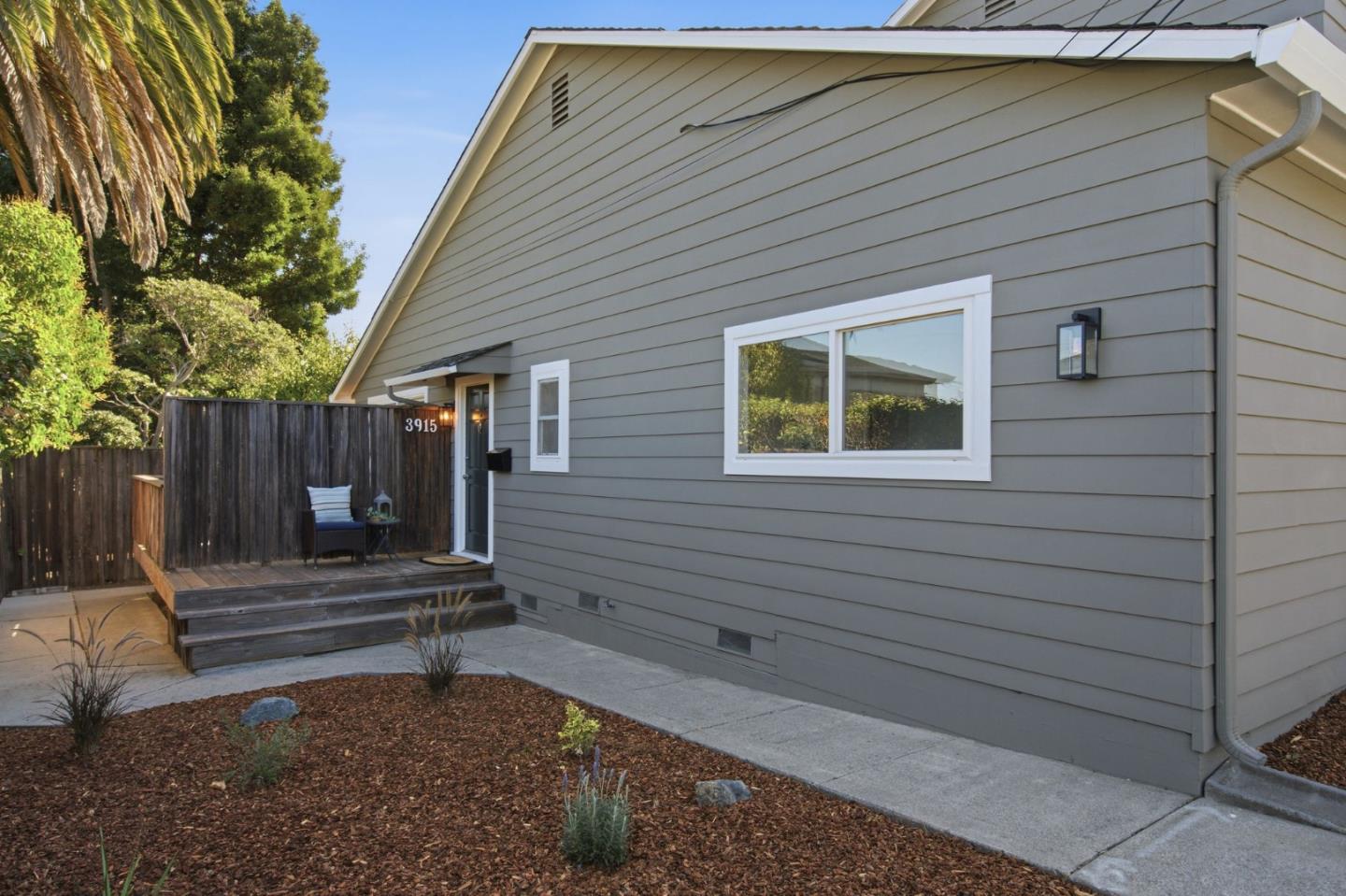 Gray-sided home with a raised deck, privacy fence, and landscaped yard.