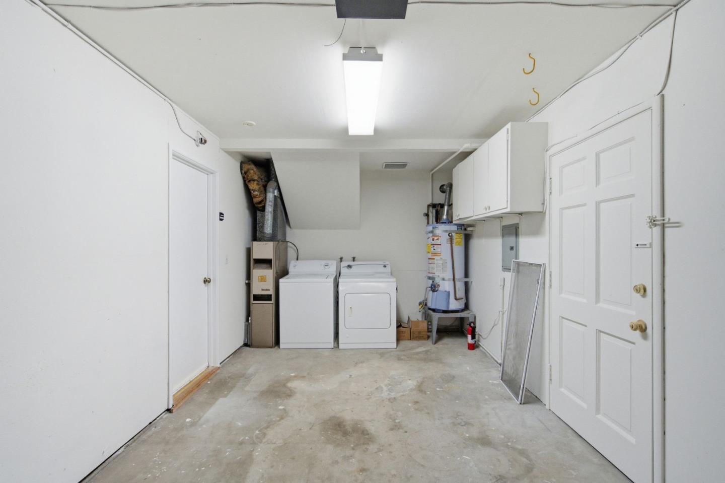 Laundry room with washer, dryer, water heater, and overhead cabinets.