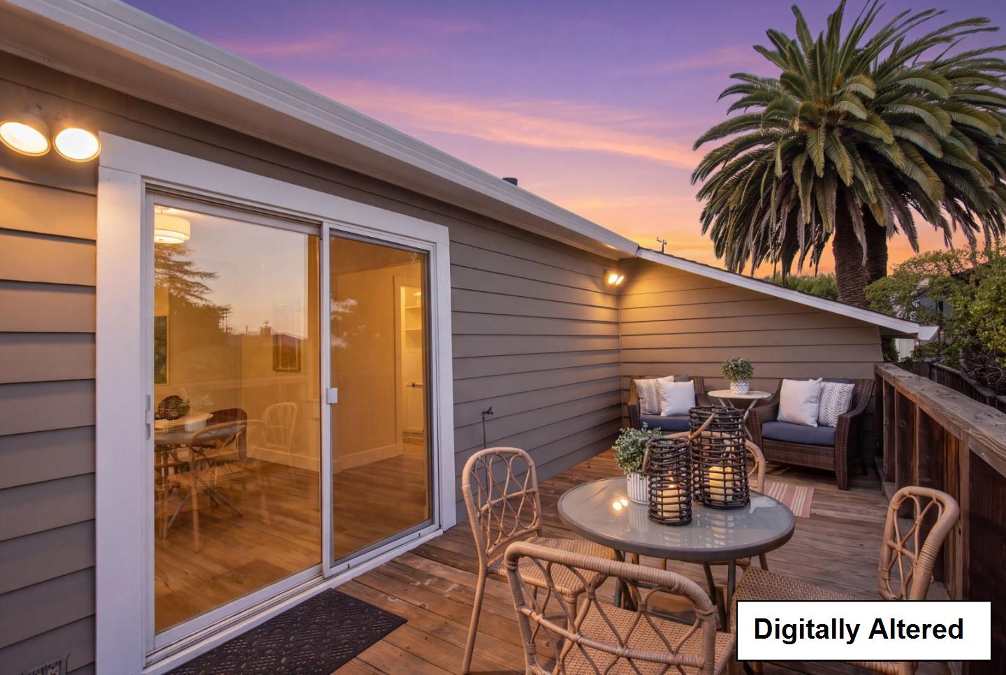 Wooden deck with wicker seating and a table beside a sliding glass door at dusk.