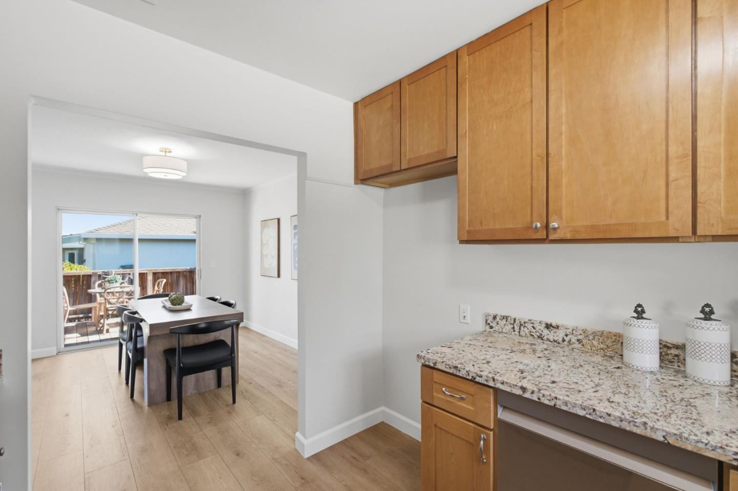 Kitchen with wood cabinets and granite counters beside a dining area opening onto a deck.