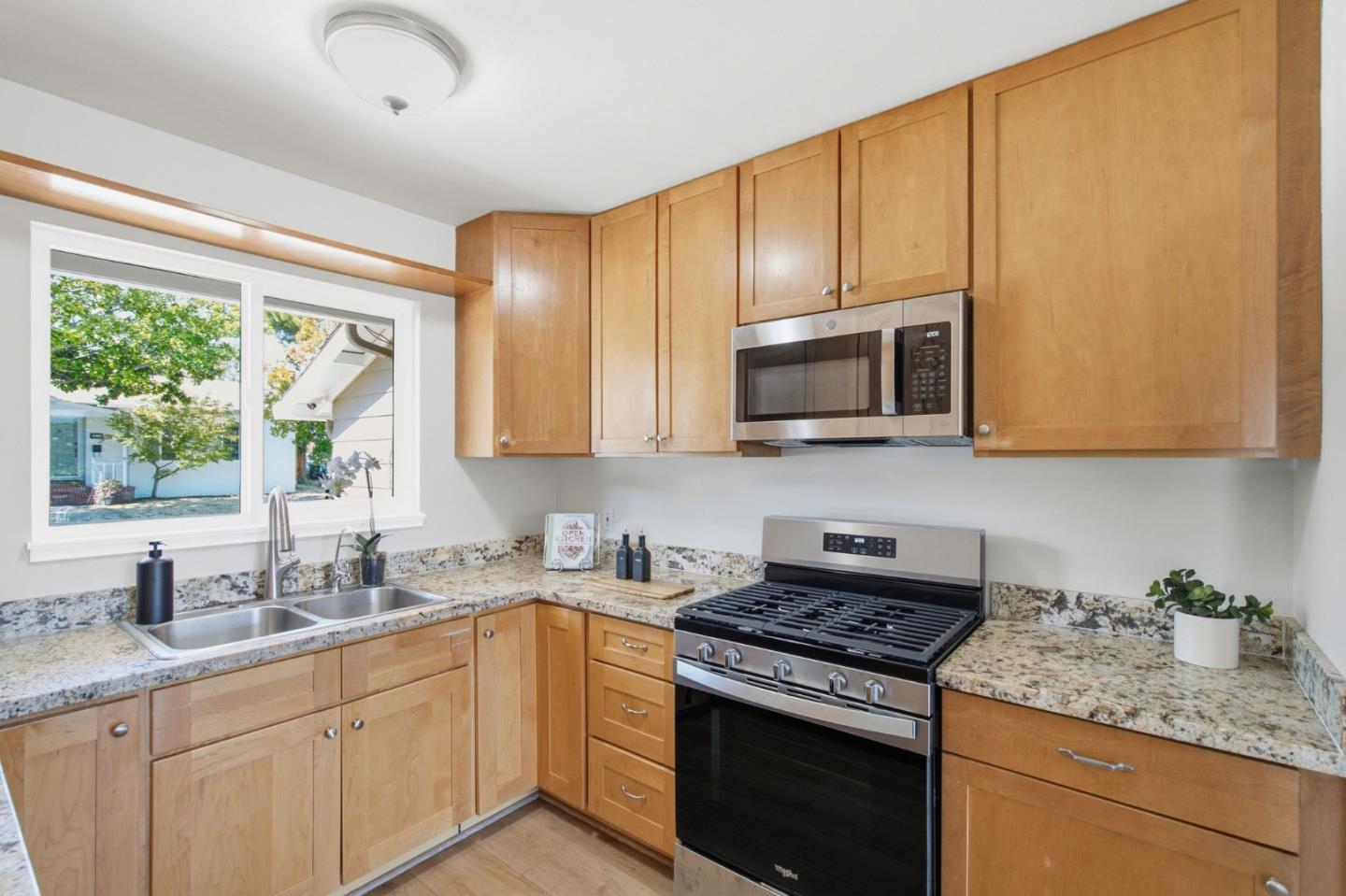 Kitchen with wood cabinetry, granite counters, and a stainless steel gas range beneath a microwave.