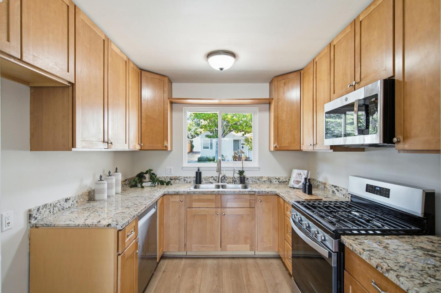 Kitchen with wood cabinets and granite counters, featuring a stainless steel range and sink beneath a window.