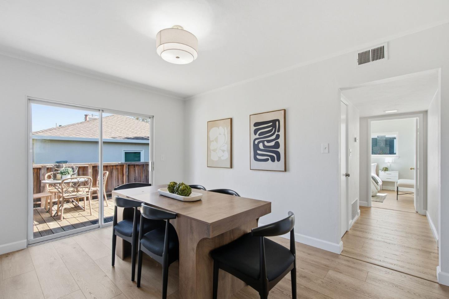Dining room with a wood table, black chairs, and sliding glass doors opening to a deck.