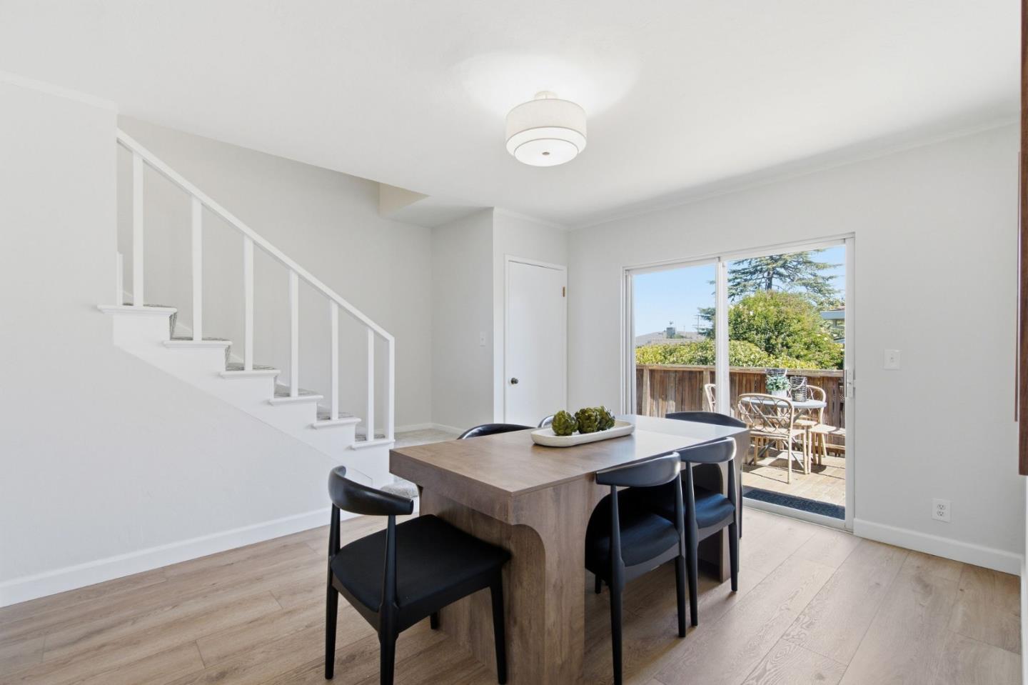 Dining area with a wood table beside stairs and sliding doors opening onto a patio.