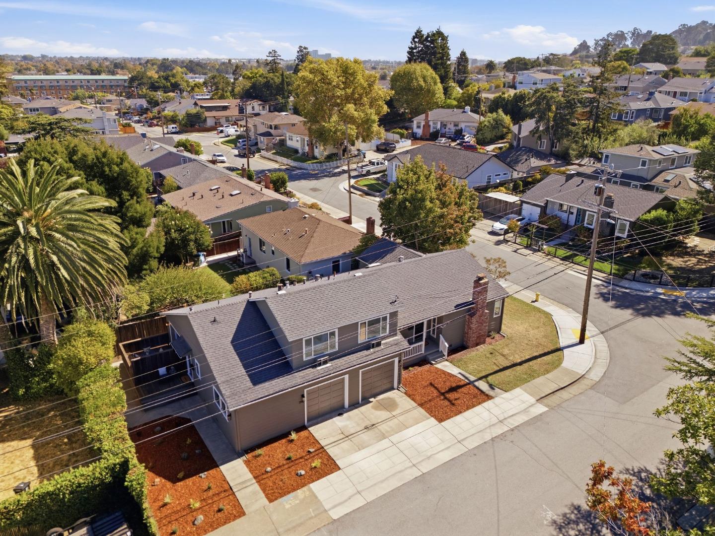 Aerial view of a gray two-story home on a corner lot with a two-car garage and rooftop solar panels.
