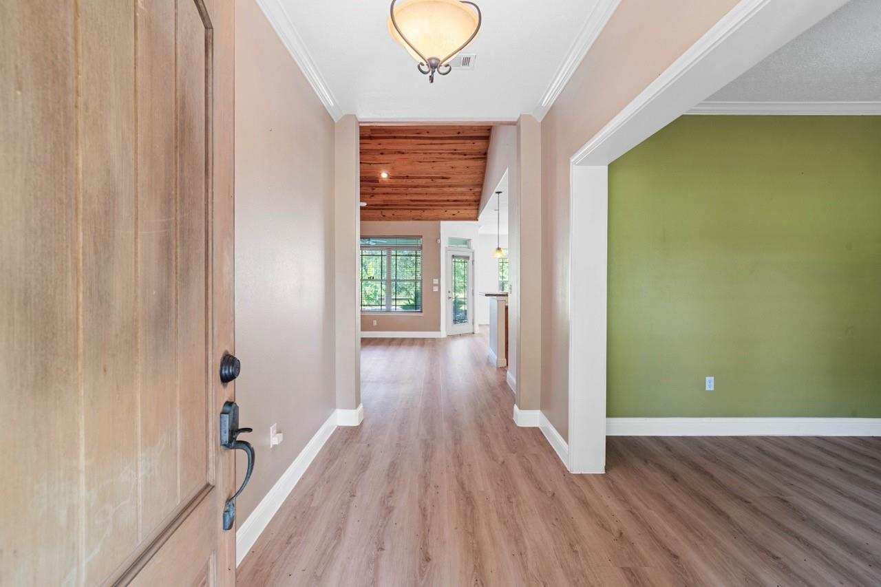Entry hall with wood-look flooring, a wood-plank ceiling, and a green-walled room off to the side.