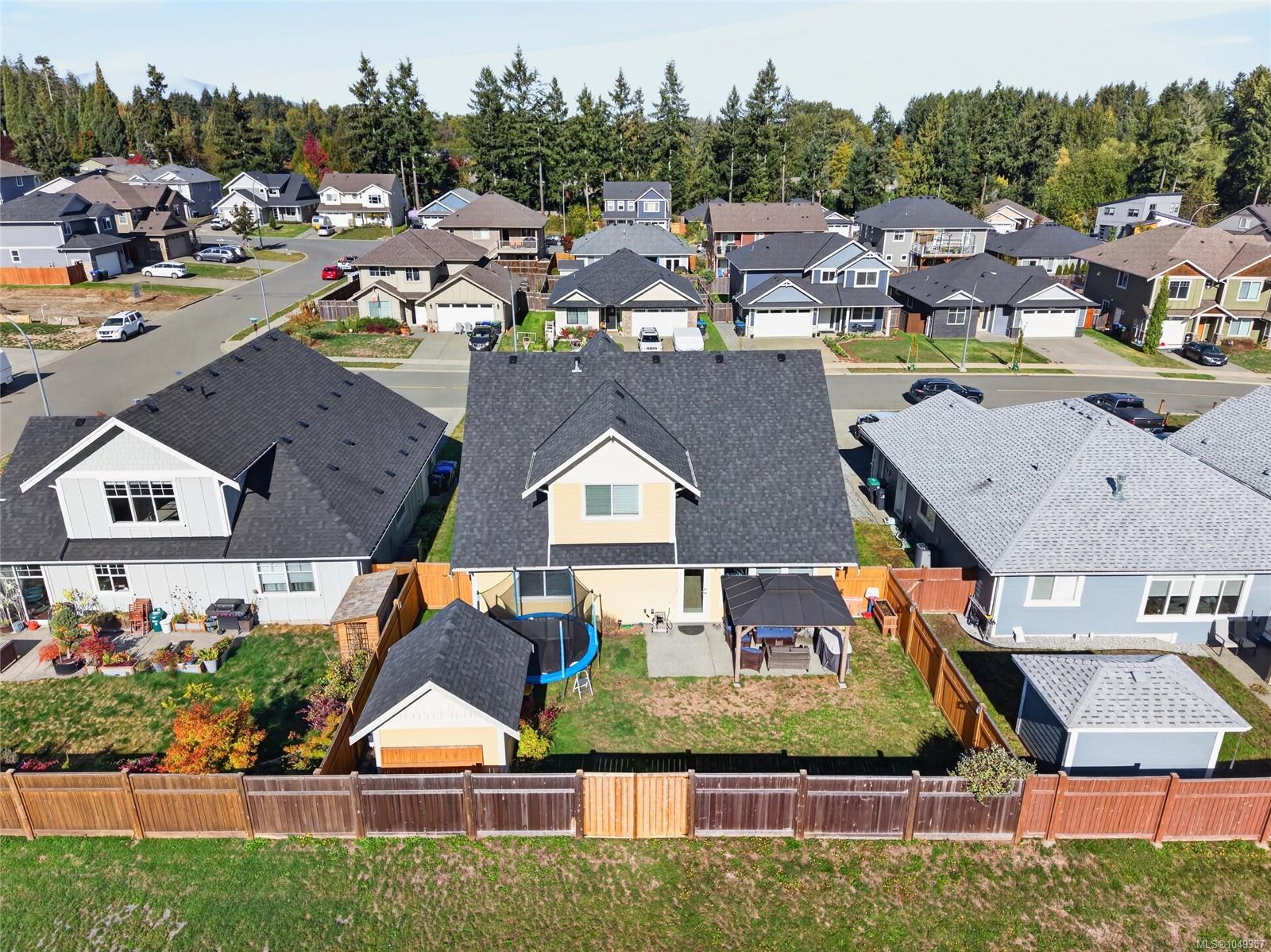Aerial view of a home with a fenced backyard, trampoline, and covered patio.