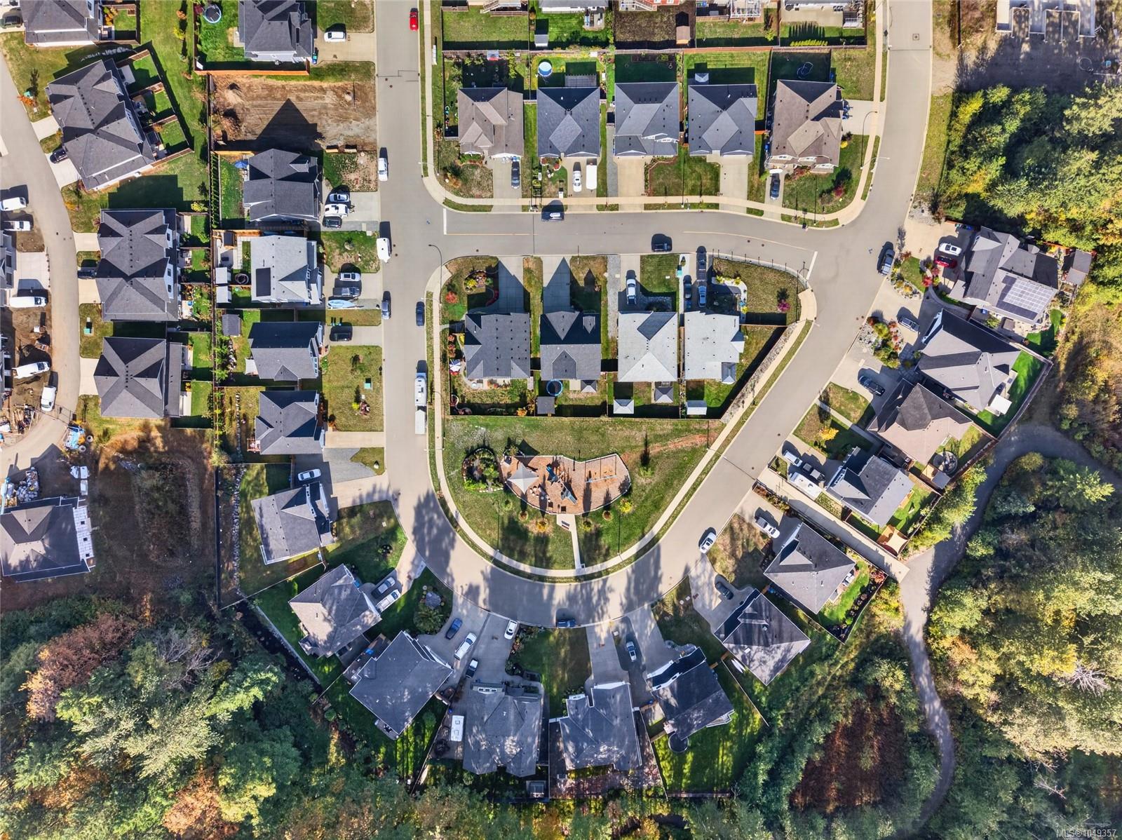 Aerial view of a residential neighborhood with detached homes around a landscaped cul-de-sac.