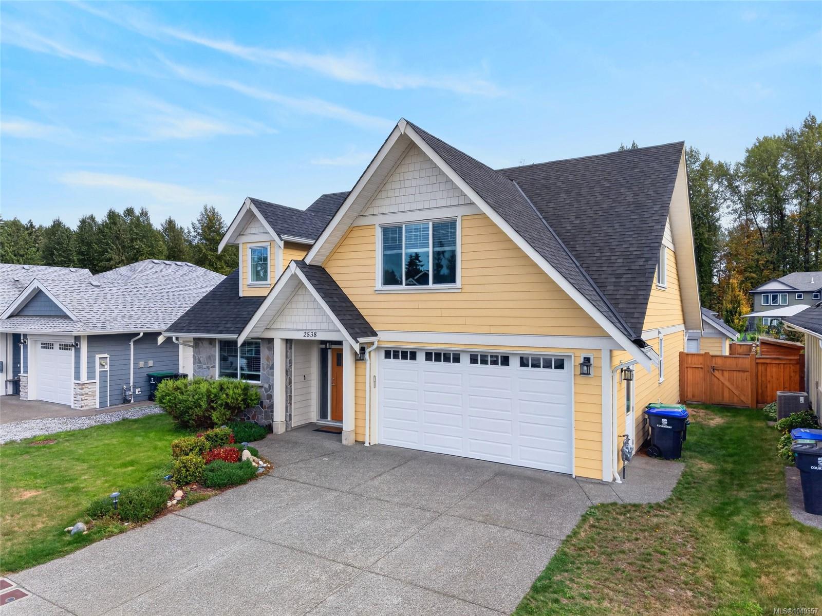 Yellow two-story house with steep gables, a double garage, and a landscaped front yard.