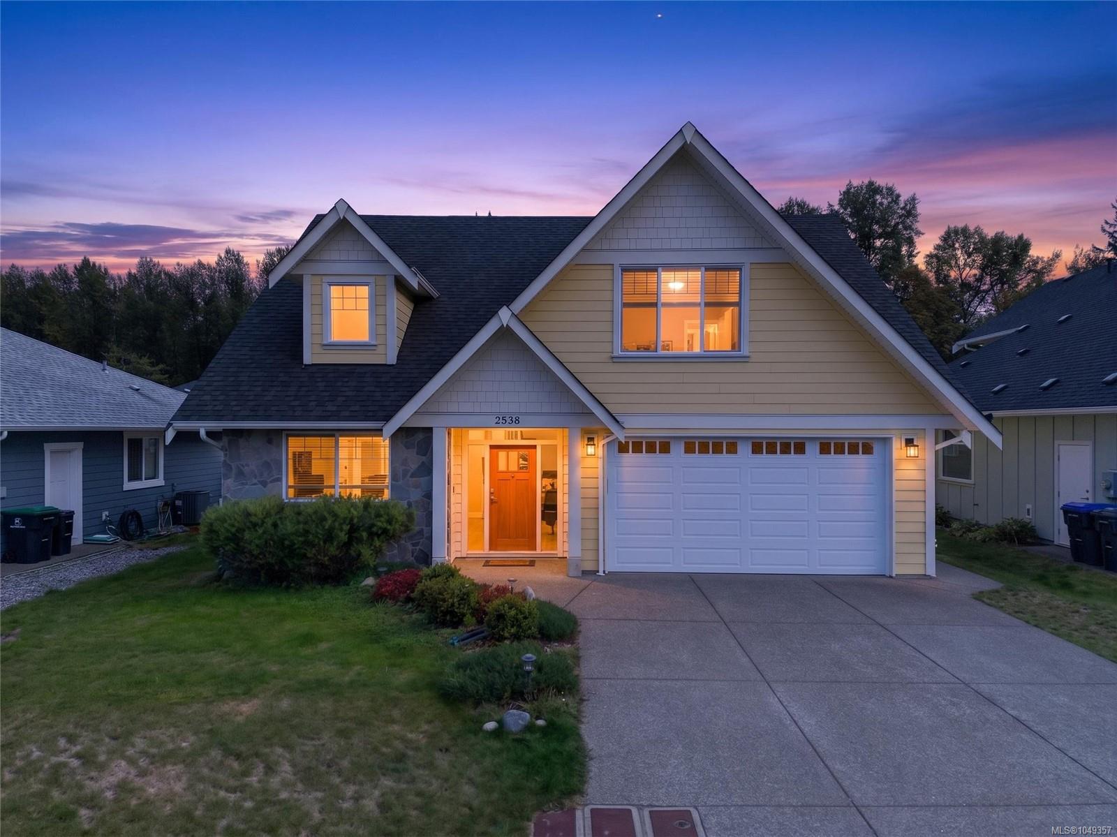 Two-story house with a double garage and warmly lit windows at dusk.