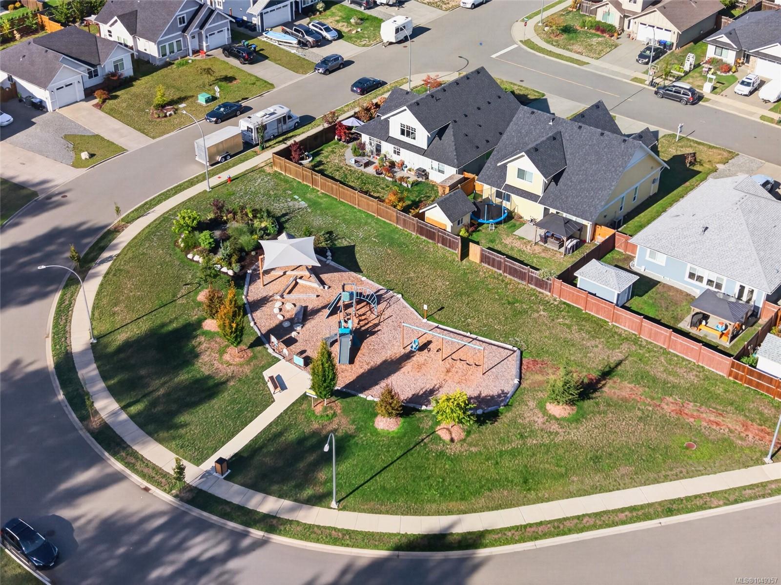 Aerial view of a home beside a neighborhood playground and fenced yards.