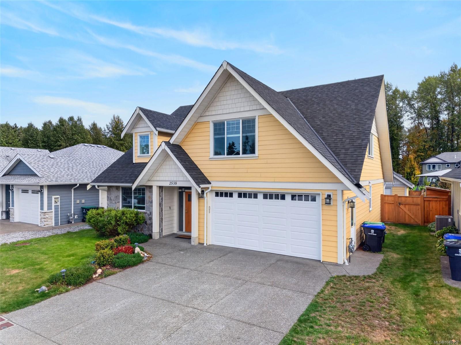 Yellow two-story house with steep gables, stone entry accents, and a double garage.