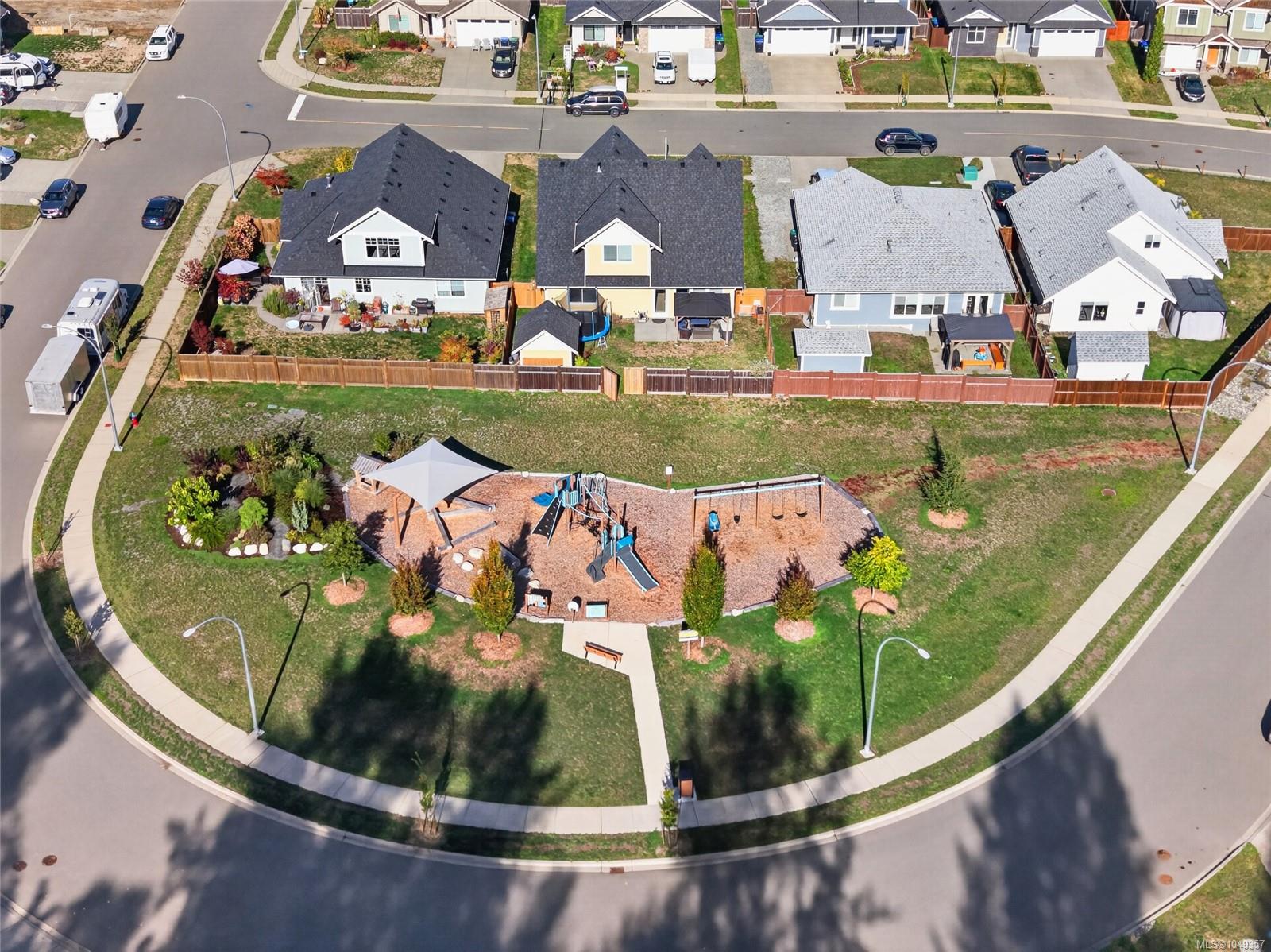 Aerial view of homes with fenced backyards beside a neighborhood playground.