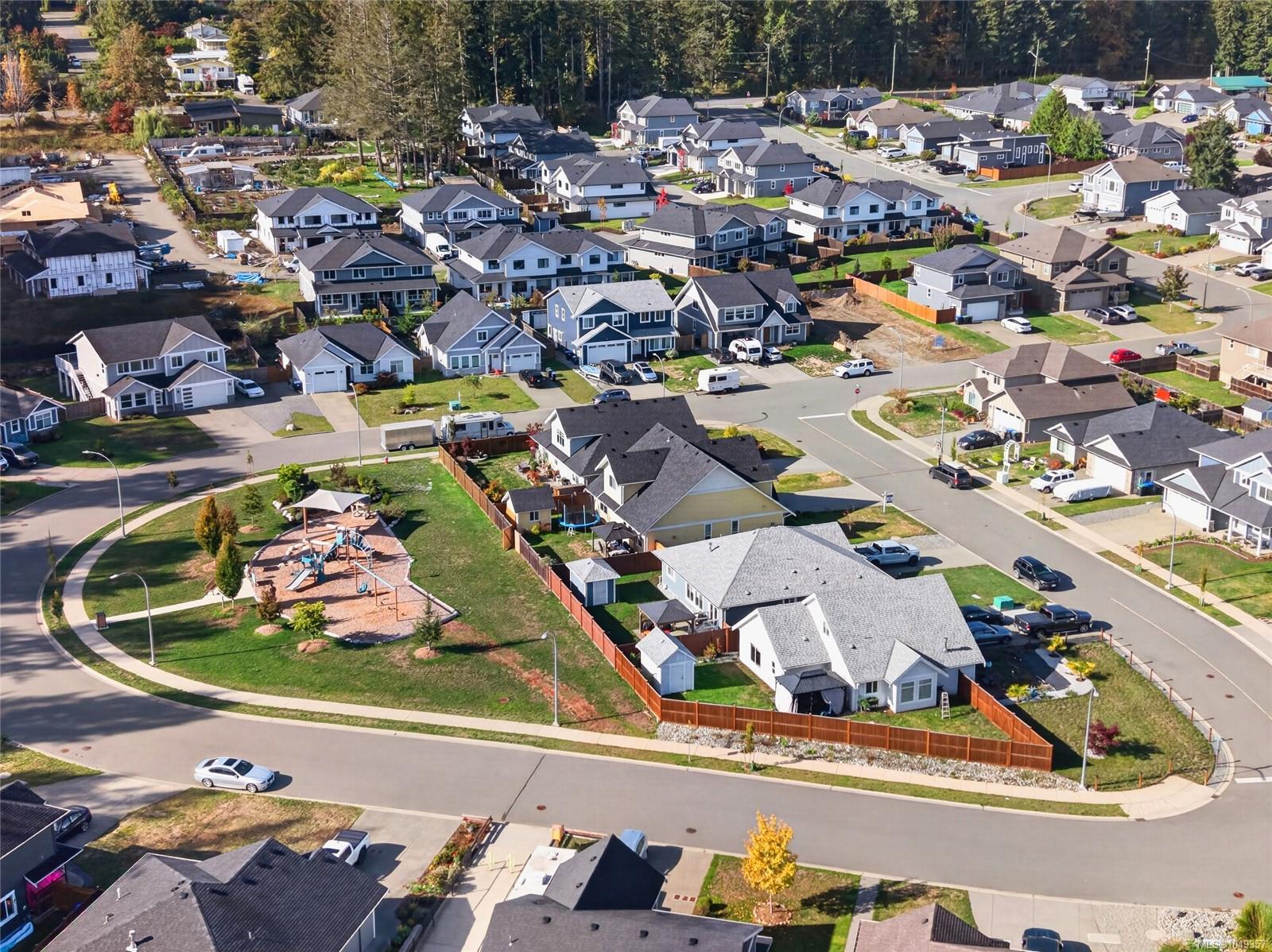 Aerial view of a residential neighborhood with a playground and forested edge.