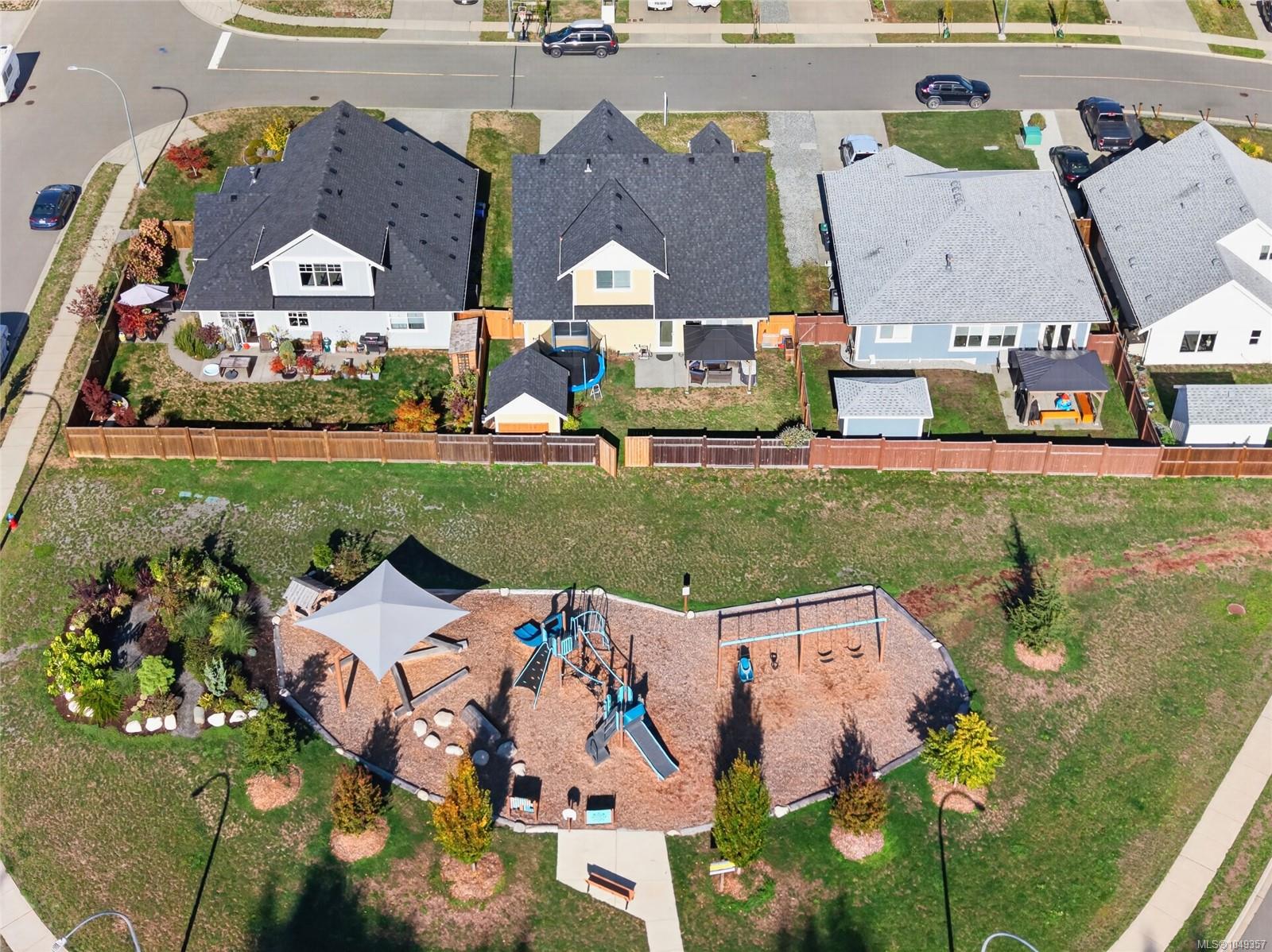 Aerial view of detached homes and fenced yards beside a landscaped playground.