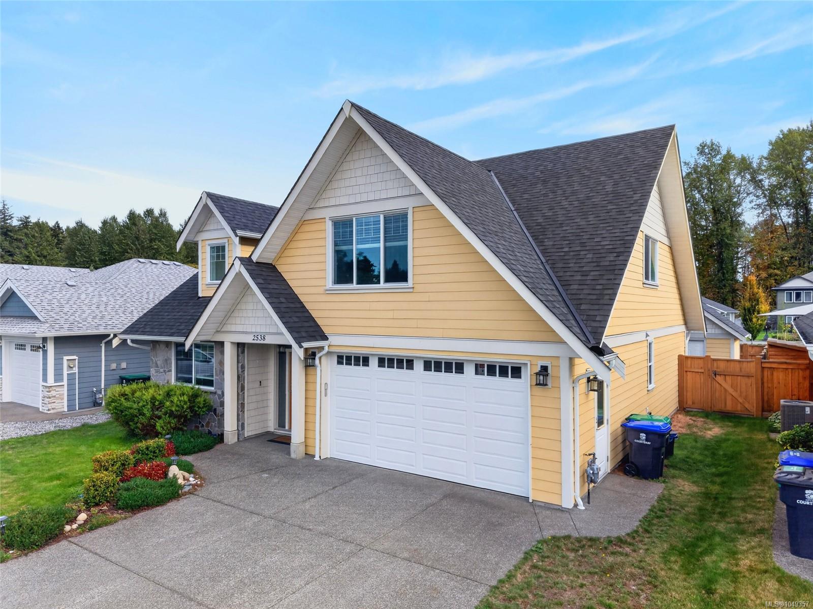Yellow two-story house with steep gables, a double garage, and a landscaped front garden.