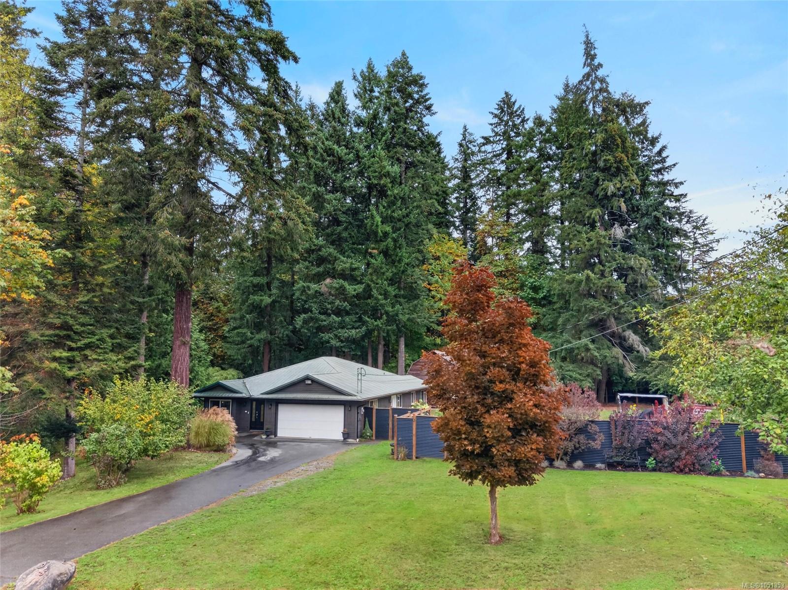 Single-story home with a double garage, surrounded by evergreens and autumn foliage.