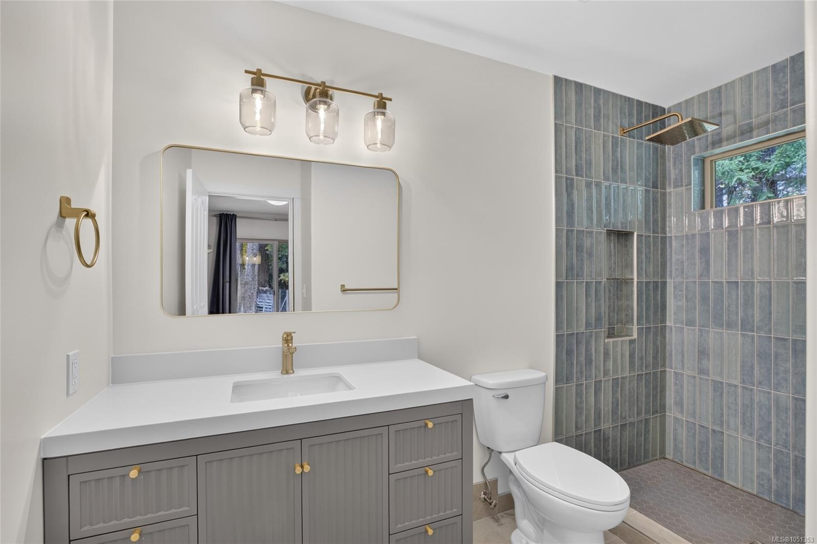Bathroom with a gray vanity and a blue-gray tiled walk-in shower.