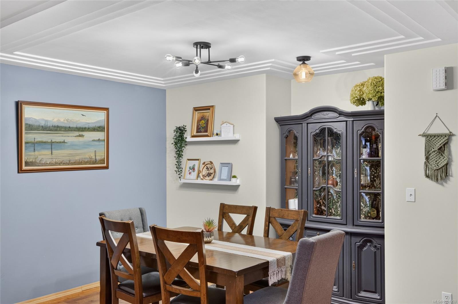 Dining room with a wooden table, cross-back chairs, and a dark glass-front china cabinet.