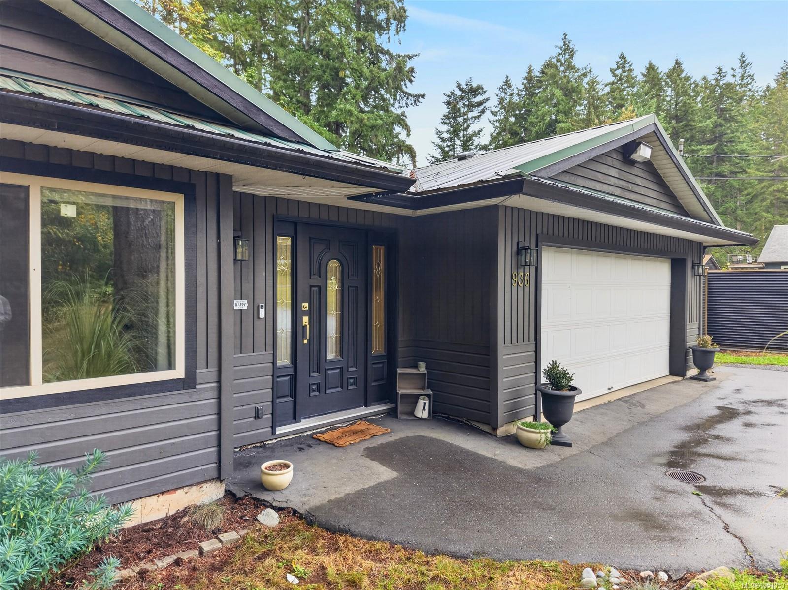 Dark gray house exterior with decorative glass entry door and white double garage door.
