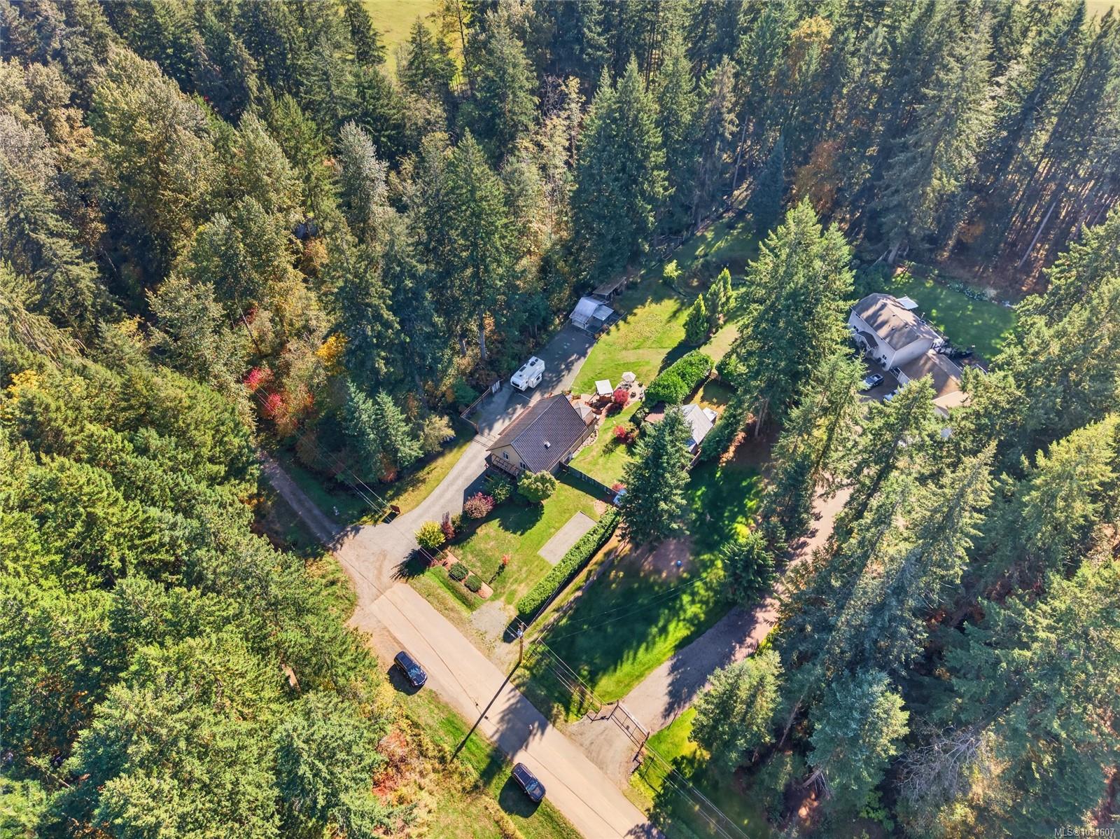 Aerial view of a home and landscaped yard surrounded by dense forest.