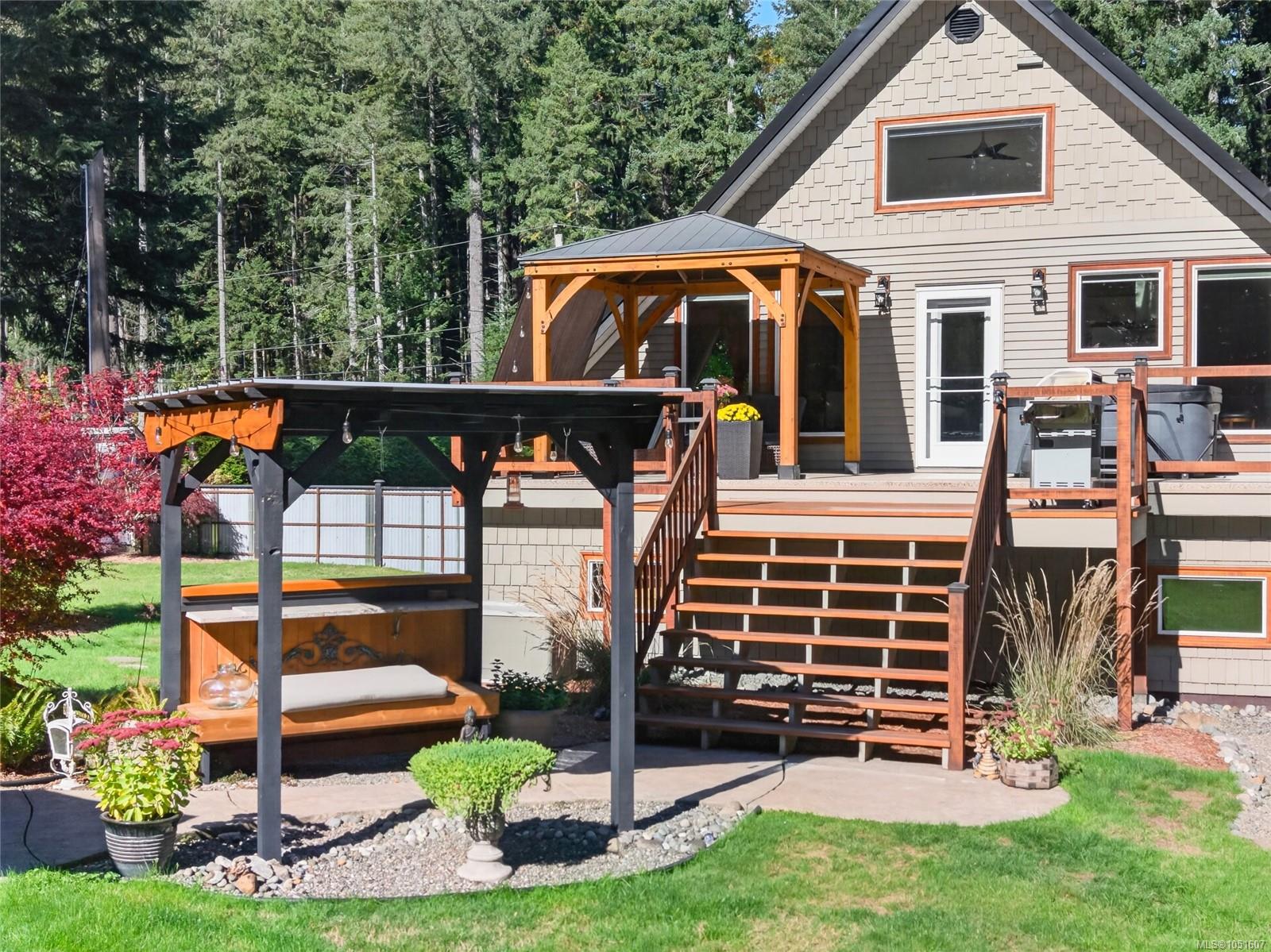 House exterior with a raised wooden deck, wide stairs, and covered patio in a landscaped yard.