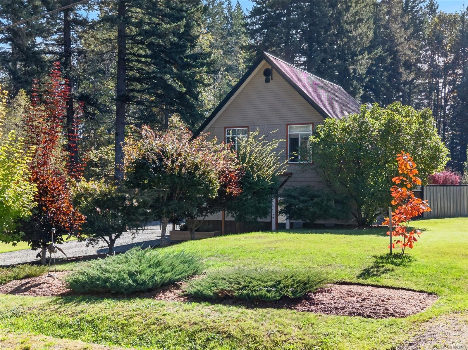 Steep-roofed home framed by evergreen trees and autumn shrubs, with a landscaped lawn.