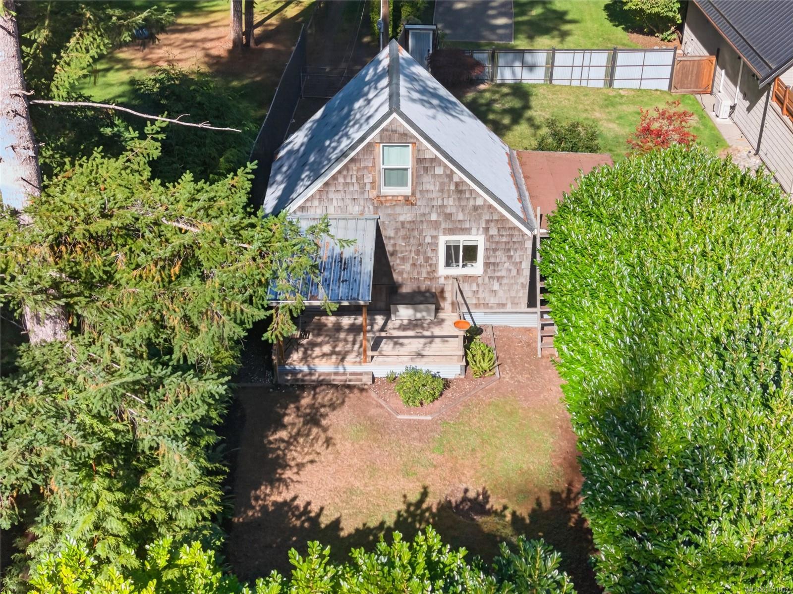 Aerial view of a cedar-shingle house and deck nestled among mature trees.