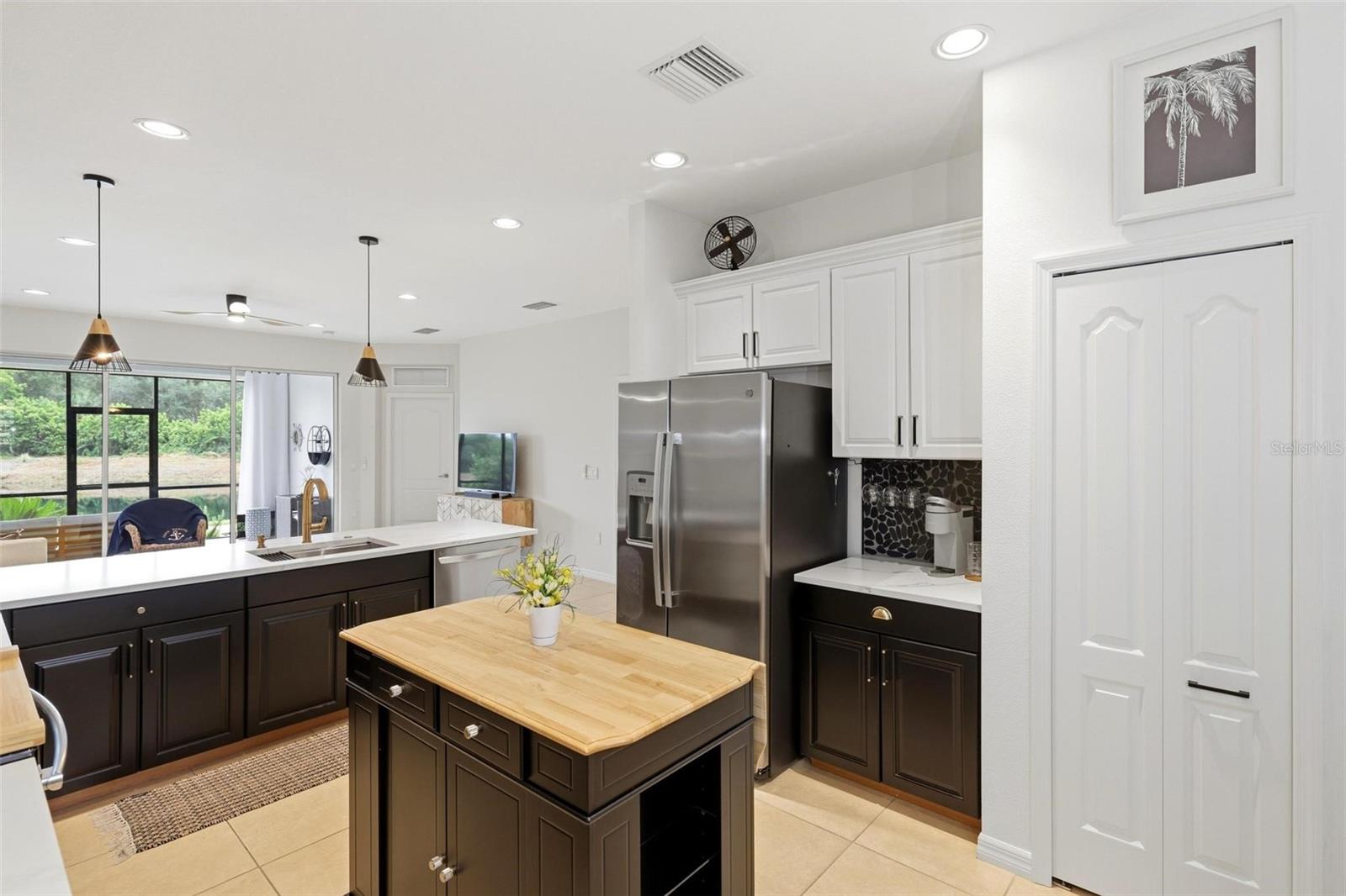 Kitchen with dark cabinets, a wood-topped island, stainless steel appliances, and sliding glass doors.