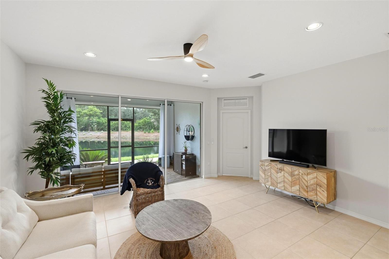 Furnished living room with sliding glass doors overlooking a waterway and greenery.