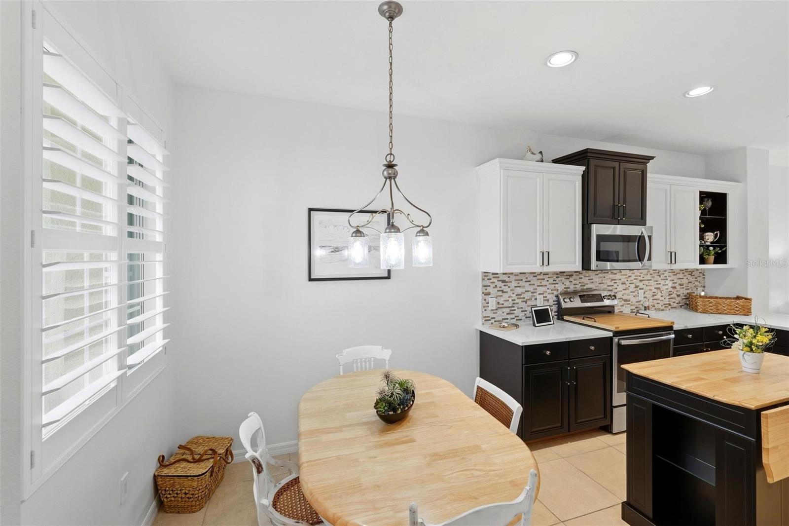 Kitchen and dining area with dark cabinetry, a wood-topped island, and a round dining table.