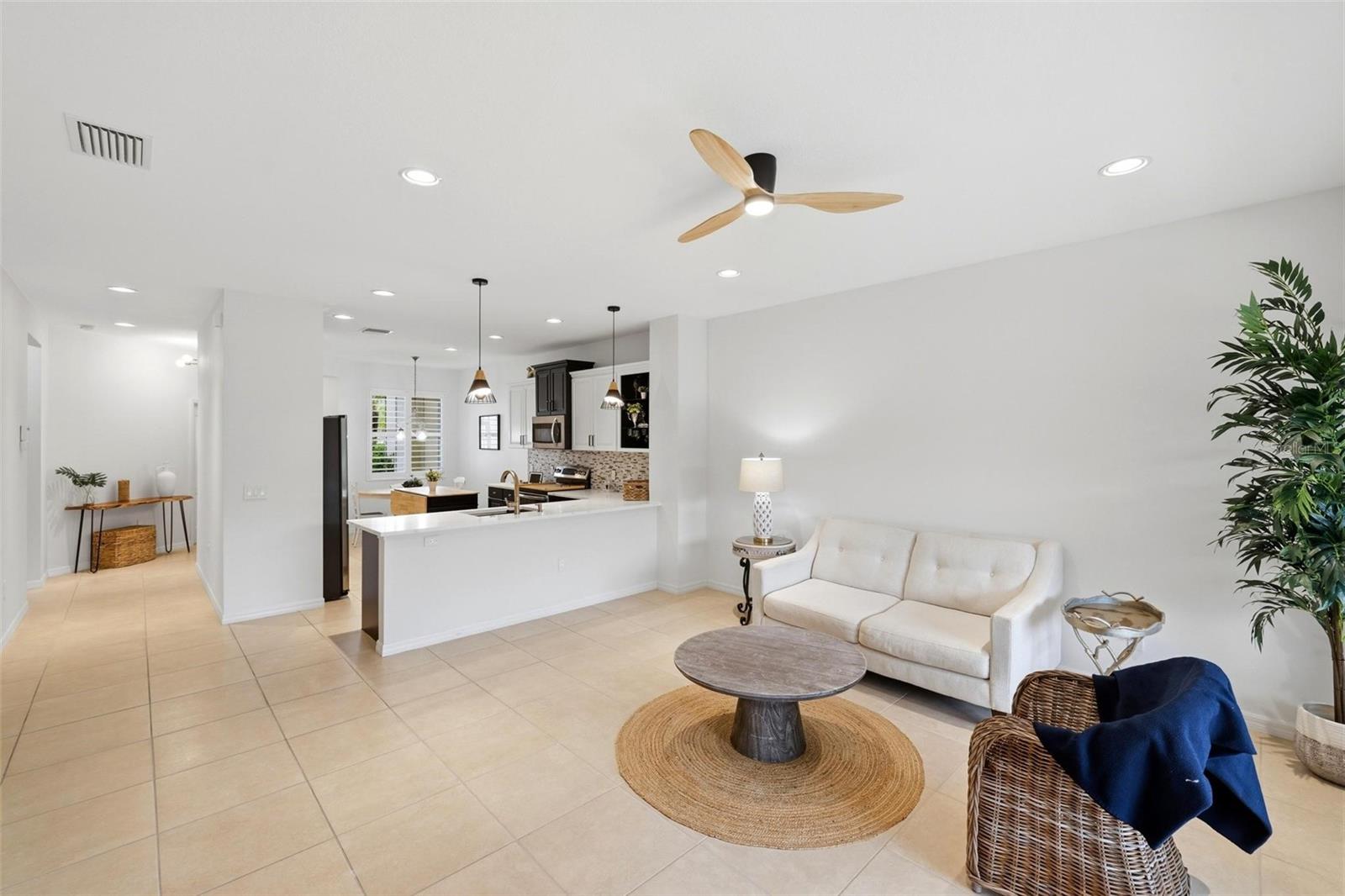 Open living room and kitchen with a white sofa, tiled floors, and a large island.