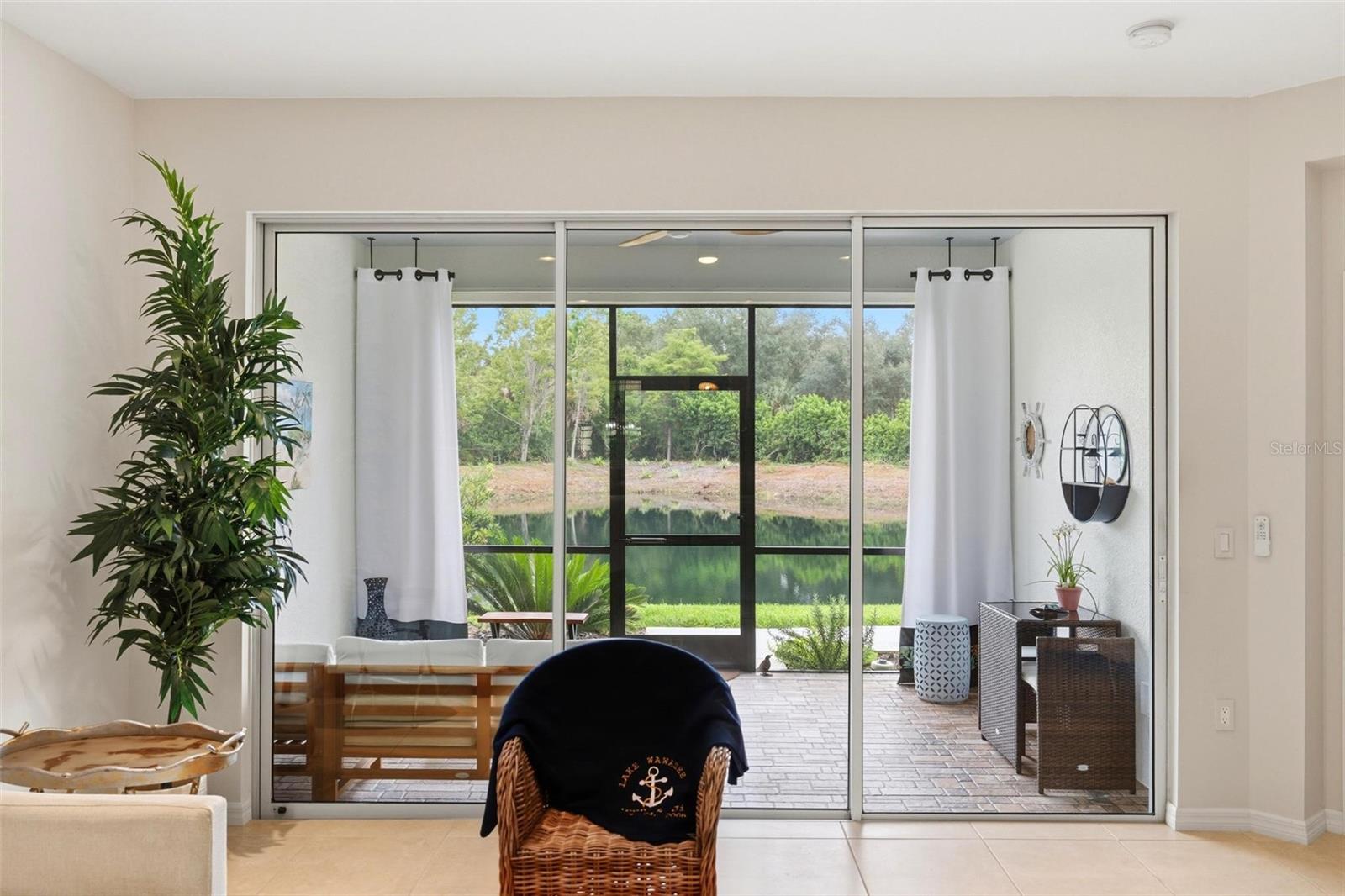 Living area with sliding glass doors opening to a screened patio overlooking a pond.