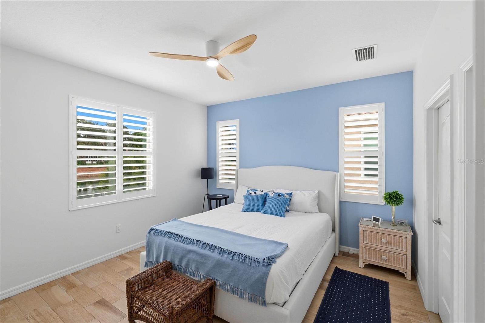 Bedroom with a white bed, blue accent wall, and plantation shutters.
