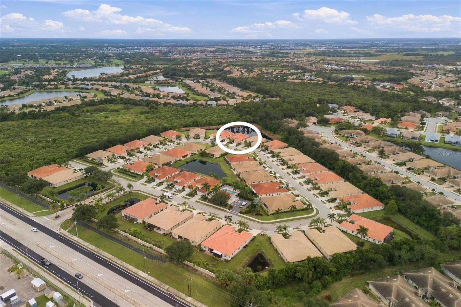 Aerial view of the home marked by a white circle in a neighborhood beside wooded wetlands.