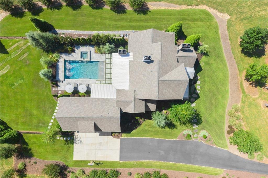 Aerial view of a large house with a backyard pool and landscaped lawn.