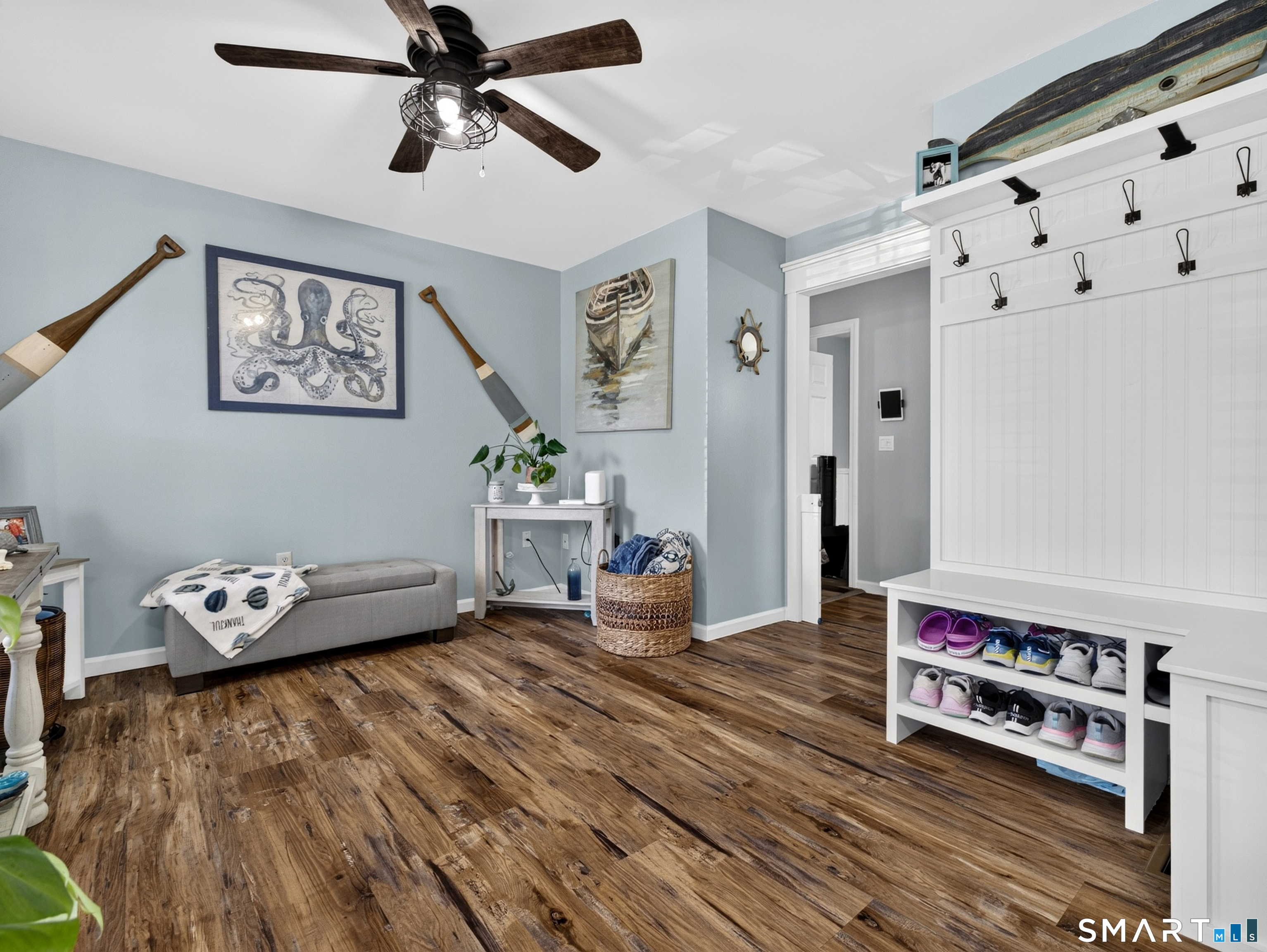 Entryway with white built-in bench and shoe cubbies, blue walls, and wood-look flooring.