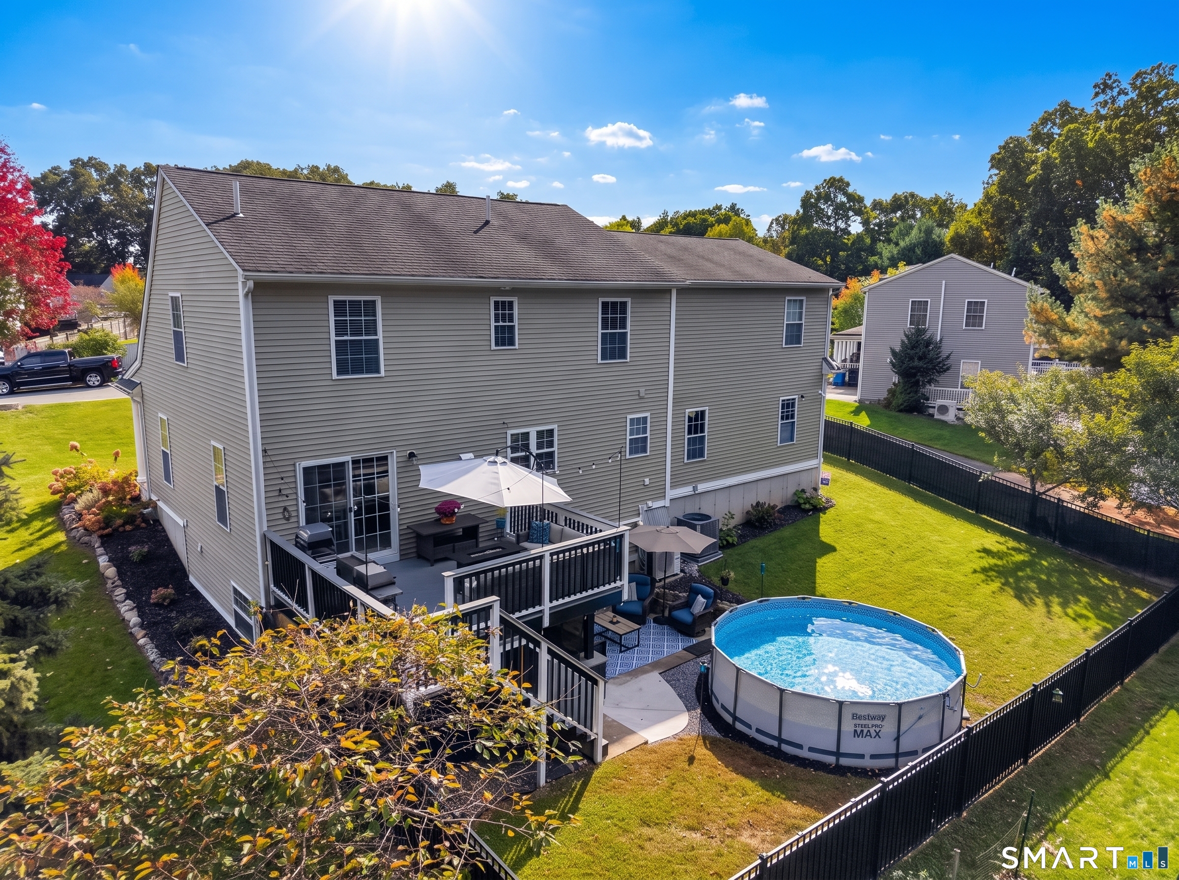 Aerial view of the home's fenced backyard, deck, and above-ground pool.