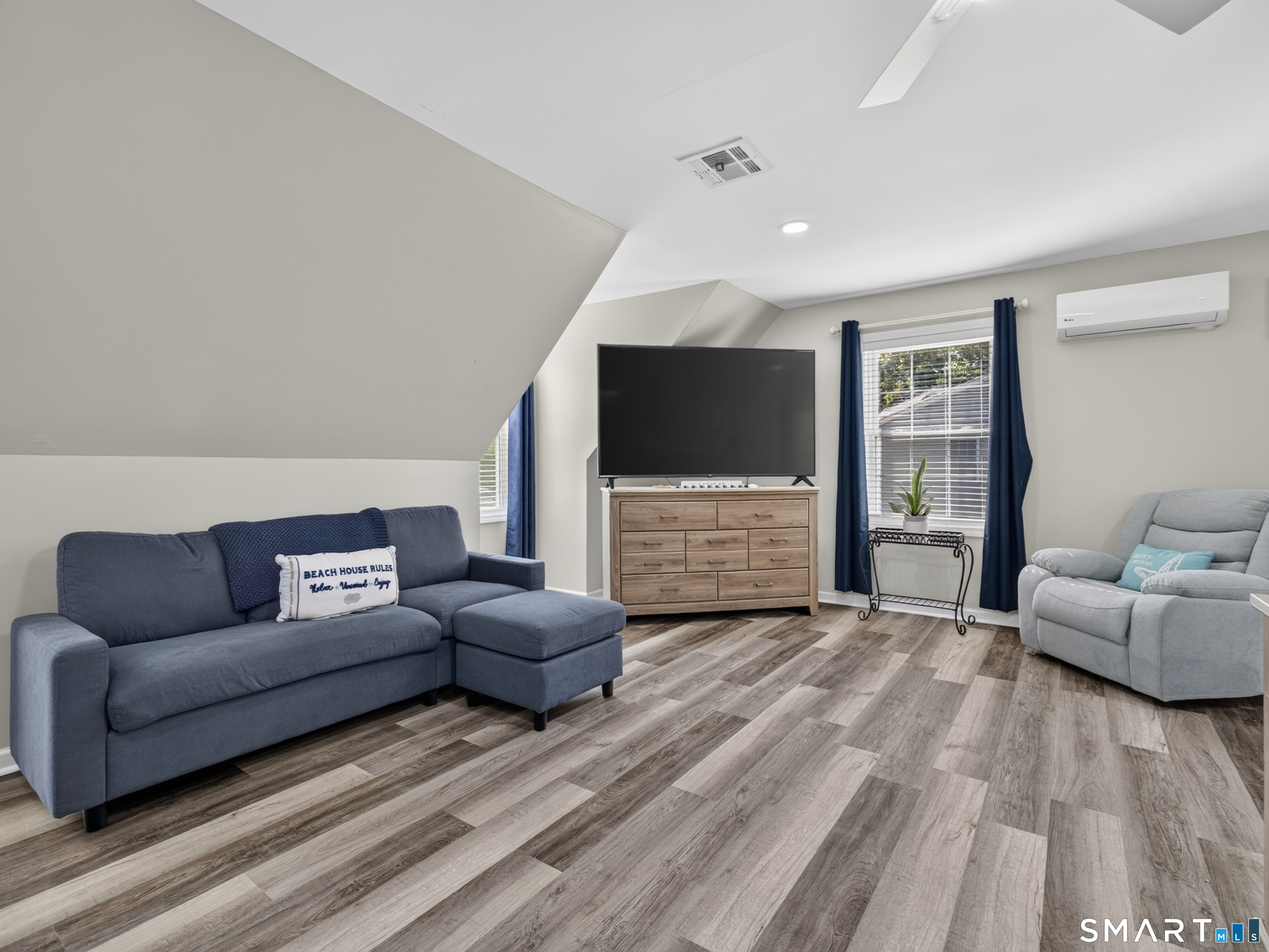 Living room with a navy sectional, gray recliner, large TV, and wood-look flooring.