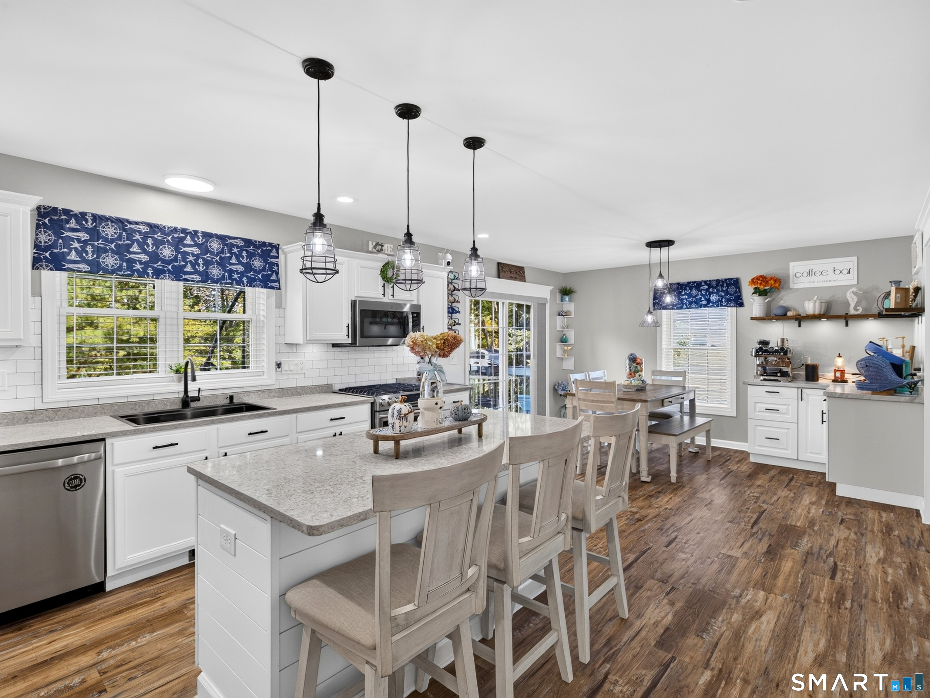 Kitchen with a large island, white cabinetry, and an adjoining dining area.